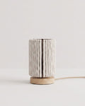 Lampe cylindre Nukumori en laine blanche sur pied en bois, éteinte, sur fond clair