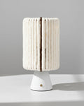 Lampe sans fil Nukumori, abat-jour en laine sur base conique blanche, éteinte, sur fond clair